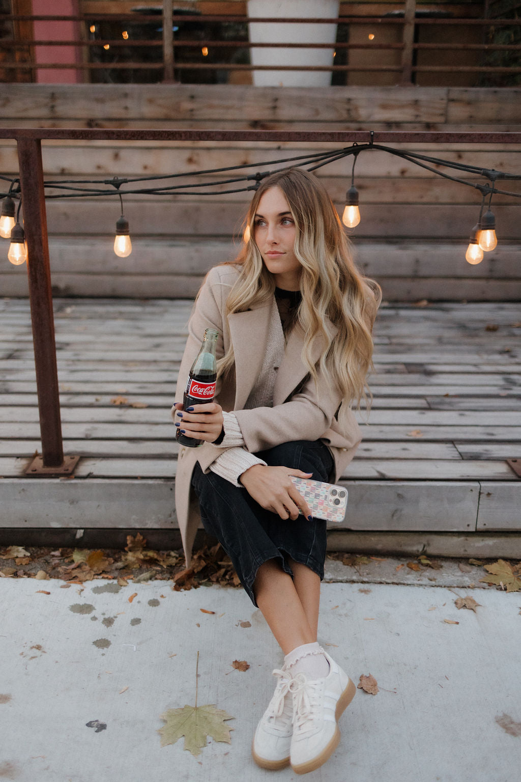 girl holding a coke bottle and a colorful phone case